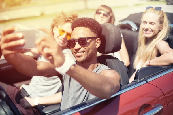 Jovens amigos tiram uma selfie em um carro cabriolet — Fotografia de Stock