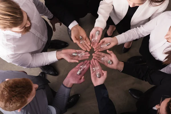 Trabajo en equipo y el concepto de lluvia de ideas con hombres de negocios que comparten una idea con una lámpara. Concepto de startup —  Fotos de Stock