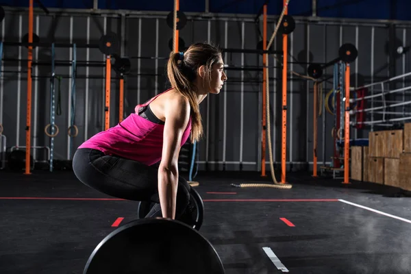 Athletische Mädchen trainiert in der Turnhalle mit einer Langhantel — Stockfoto