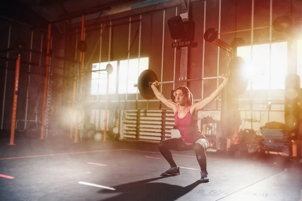 Athletische Mädchen trainiert in der Turnhalle mit einer Langhantel — Stockfoto
