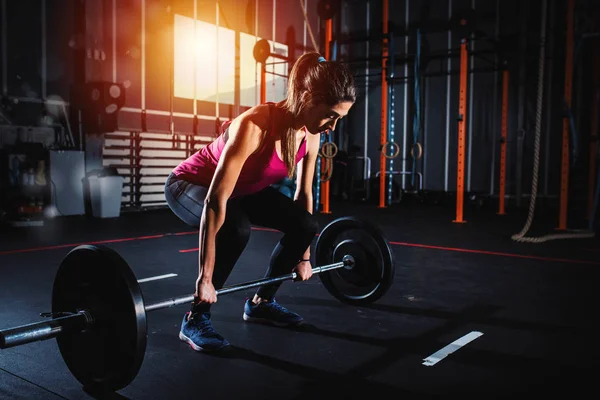 Menina atlética trabalha no ginásio com um barbell — Fotografia de Stock