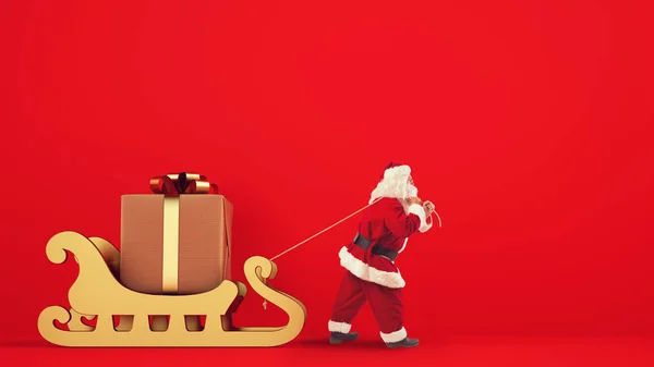 Santa Claus drags a big gift with a golden sleigh on a red background — Stock Photo, Image