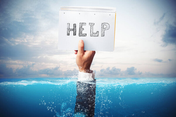 Businessman drowning in the sea with a hand holding a sheet of paper with help written