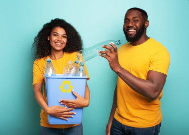 Mutlu çift açık mavi renkli bir şişenin üzerinde plastik bir kap tutuyor. Ekoloji, koruma, geri dönüşüm ve sürdürülebilirlik kavramı