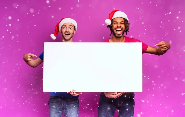 깜짝 놀란 친구들이 크리스마스 모자를 쓰고 메시지를 전하기 위해 흰 깃발을 들고 있습니다. 보라색 배경 — 스톡 사진