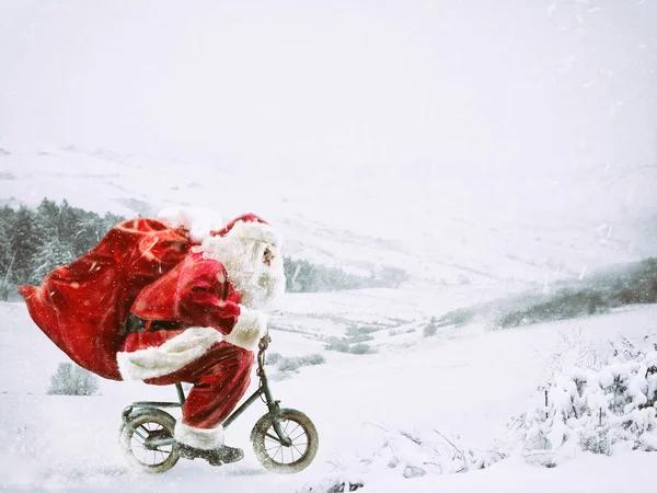 Weihnachtsmann auf einem kleinen Fahrrad in einer Winterlandschaft unter dem Schnee — Stockfoto