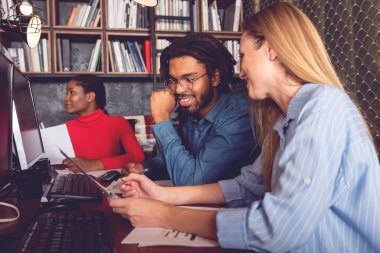 Genç gülümseyen iş adamı ve kadın ofiste birlikte çalışarak elde edilen olumlu sonuçları analiz ediyorlar.