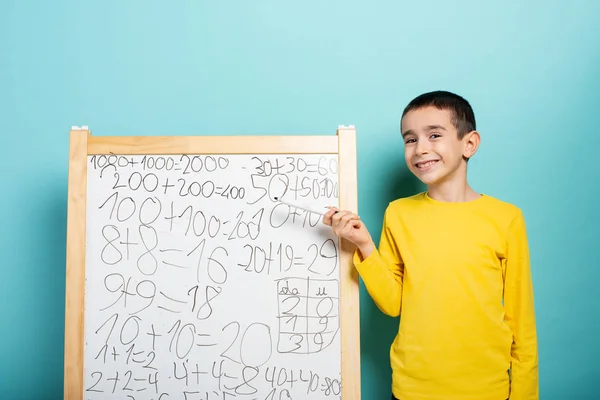 Child solves mathematical problem with abacus. Cyan background — ストック写真