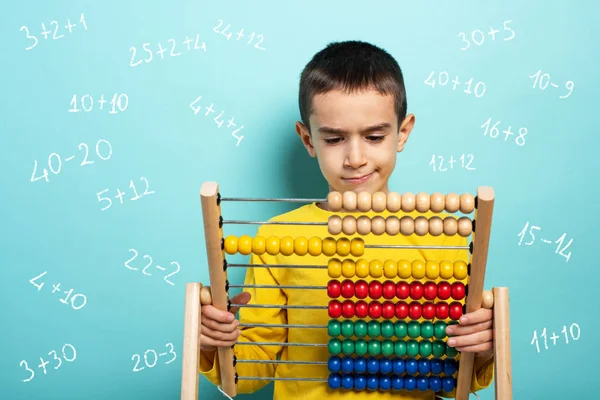 Criança tenta resolver problema matemático com ábaco. Contexto ciano — Fotografia de Stock