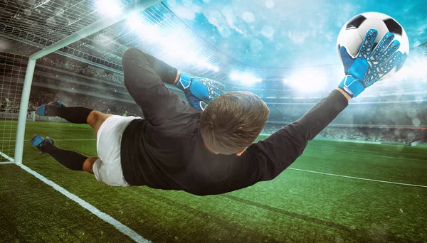 Вратарь ловит мяч на стадионе во время футбольного матча — стоковое фото
