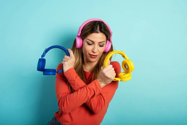 Girl with headset listens to music and dances. emotional and energetic expression. Cyan background — Stock Photo, Image