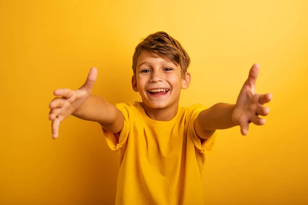 Criança feliz e alegre quer abraçar alguém. Cor de fundo amarelo — Fotografia de Stock