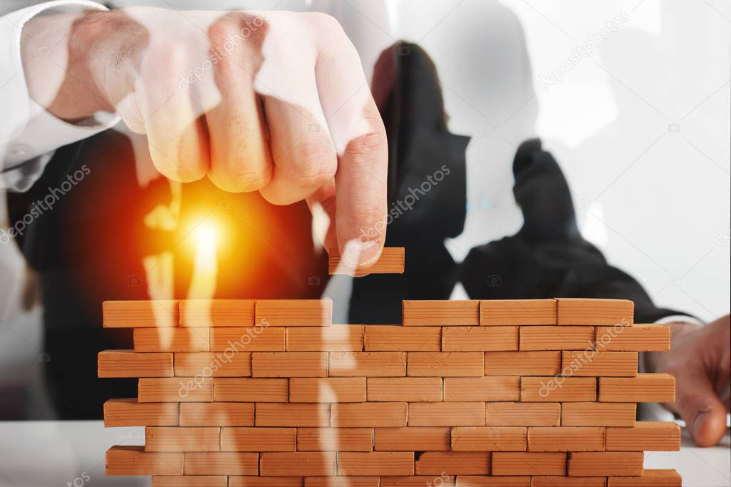 Businessman puts a brick to build a wall. Concept of new business, partnership, integration and startup.