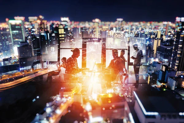 Silhouet van jonge zakenmensen werken 's nachts samen in het kantoor op een skyline achtergrond — Stockfoto