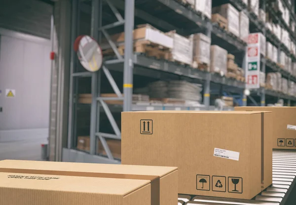 Cajas de cartón en rodillos transportadores dentro de un almacén listo para ser enviado por mensajero para su distribución — Foto de Stock