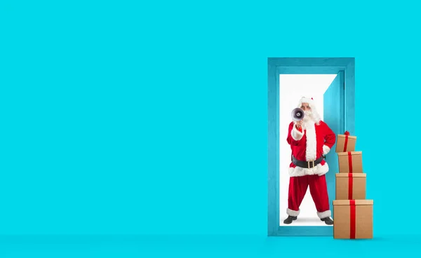 サンタクロースはクリスマスの日の贈り物を配達するためにドアの後ろのメガホンで叫んでいます。船のコンセプト — ストック写真