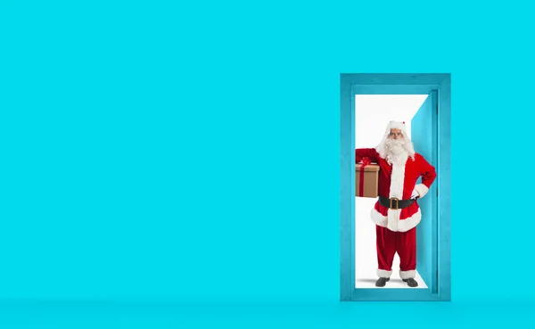 Papai Noel atrás da porta para entregar um presente para o dia de Natal. Conceito de transporte — Fotografia de Stock