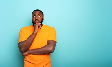 Bir çocuğun kafa karışıklığı ve düşünceli ifadesi. cyan renkli arkaplan