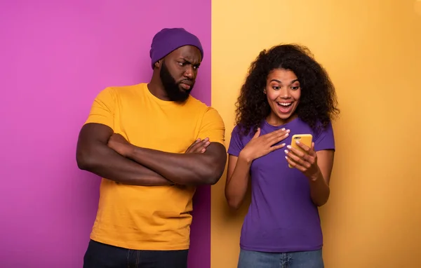 Menina receber um monte de lareiras em social e menino está com ciúmes sobre isso. Fundo amarelo e violeta — Fotografia de Stock