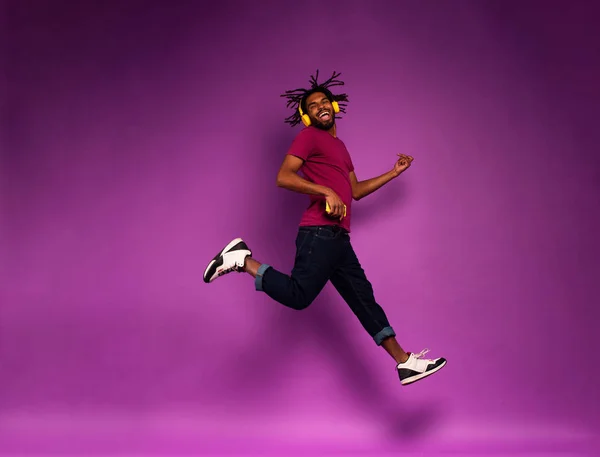 Niño con auriculares amarillos escucha música y bailes. expresión emocional y energética —  Fotos de Stock