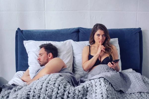 Girlfriend secretly chatting with others while he sleeps. Infidelity concept — Stock Photo, Image