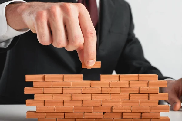 Affärsman sätter en tegel för att bygga en mur. Begreppet nya affärer, partnerskap, integration och start. — Stockfoto