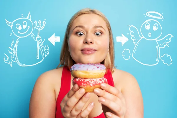 Dikke meid denkt om donuts te eten in plaats van gym. Concept van besluiteloosheid en twijfel met engel en duivel suggestie — Stockfoto
