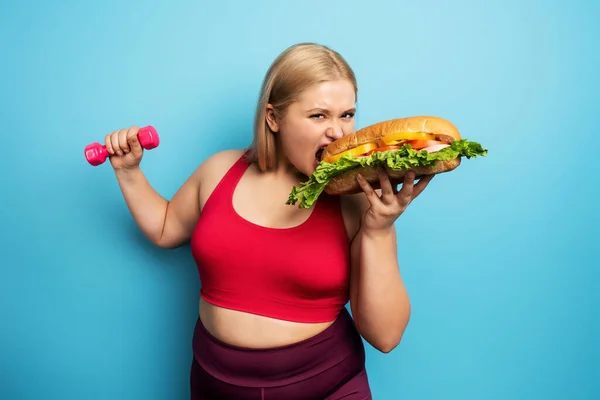 A gorda faz ginástica e quer comer uma sanduíche. Conceito de indecisão e dúvida — Fotografia de Stock