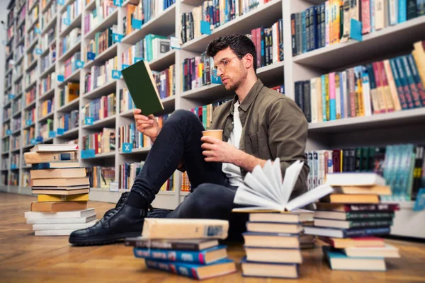 O rapaz lê um livro numa biblioteca. Conceito de curiosidade, imaginação e cultura — Fotografia de Stock