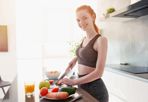 Atletica ragazza con abiti da palestra mangia frutta in cucina — Foto Stock