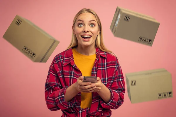 Sarışın tatlı kız çevrimiçi siparişten öncelikli hızlı kutular alıyor. Şaşırtıcı ve hayret verici bir ifade. Pembe arkaplan — Stok fotoğraf