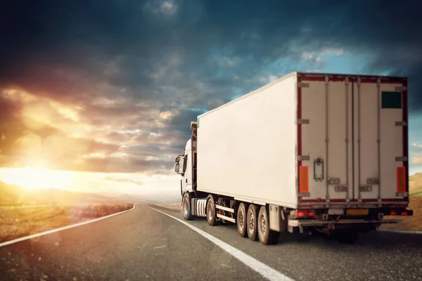 Camion bianco che si muove sulla strada in un paesaggio naturale al tramonto . — Foto Stock