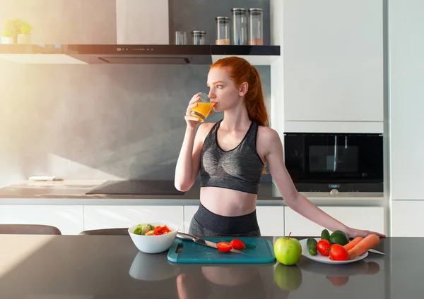 Spor elbiseli atletik kız mutfakta meyve yiyor. — Stok fotoğraf