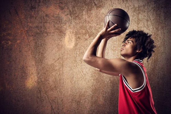 Jogador de basquete joga a bola no fundo marrom grunge — Fotografia de Stock