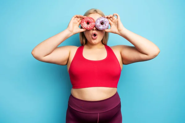 Dicke Mädchen denken, Donuts zu essen, anstatt Sport zu treiben. Konzept der Unentschlossenheit und des Zweifels — Stockfoto