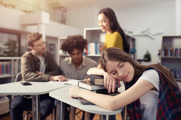 Moe meisje slaapt boeken tijdens een ontmoeting met studenten. Concept van stress en overwerk — Stockfoto