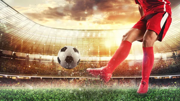 Футбольная сцена на стадионе с игроком в красной форме, пинающим мяч — стоковое фото