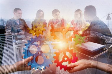 İş ekibi dişli parçalarını birbirine bağlıyor. Takım çalışması, ortaklık ve bütünleşme kavramı