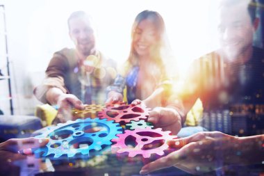 İş ekibi dişli parçalarını birbirine bağlıyor. Takım çalışması, ortaklık ve bütünleşme kavramı