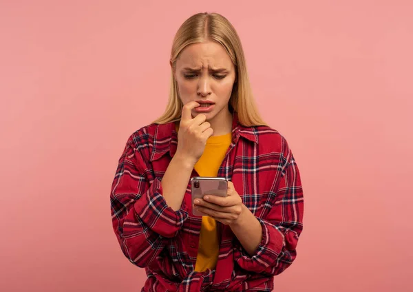 Girl with her smartphone. scared and afraid expression. Pink background — Zdjęcie stockowe
