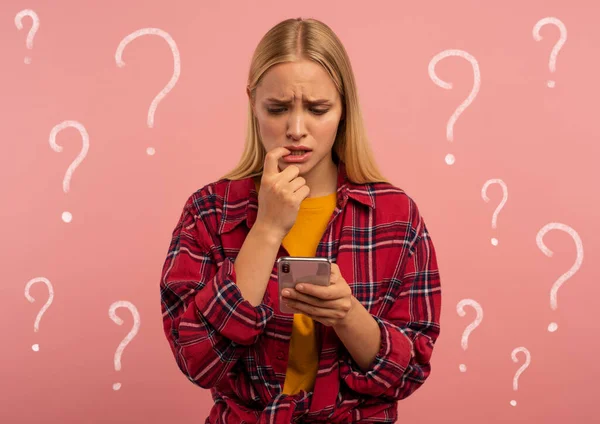 Girl with her smartphone. scared and afraid expression. Pink background — Stok fotoğraf