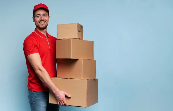 Courier has a lot of boxes to delivery. Emotional expression. Cyan background — Stock Photo, Image