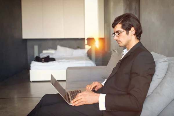 Молодой бизнесмен сидит на полу, работая из дома с ноутбуком — стоковое фото