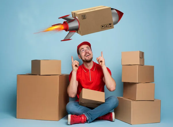 Courier is happy because boxes are delivery fast like a rocket. Studio on cyan background — Stock Photo, Image