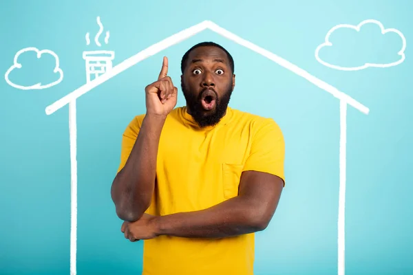 Man is amazed to have bought a house. Cyan background — Stock Photo, Image