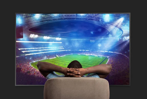 Büyük bir televizyonun önündeki izleyici evde spor maçı izlerken koltukta dinleniyor. — Stok fotoğraf