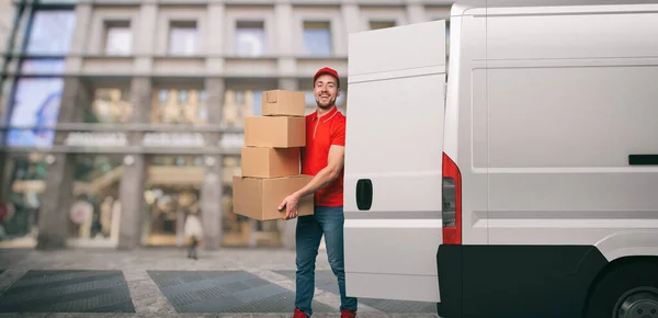 Rode koerier buiten vervoert pakketten met een withe busje voor leveringen van zendingen. — Stockfoto