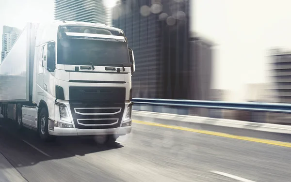 White truck moving fast on the highway with a modern city in the background — Stock Photo, Image