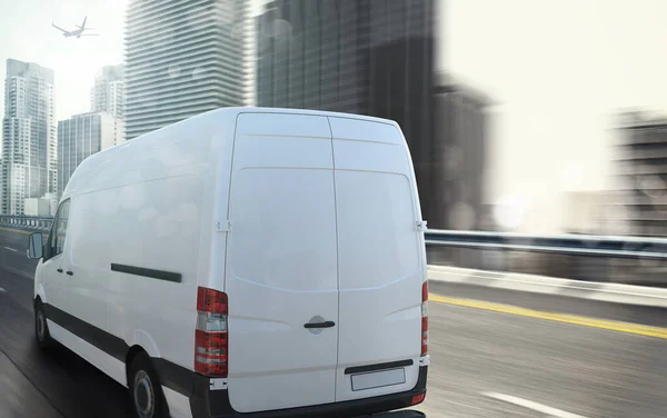 Vit van rör sig snabbt på motorvägen med en modern stad i bakgrunden — Stockfoto