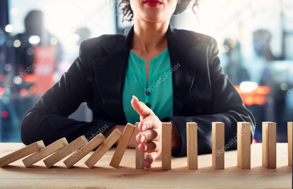 Businesswoman stops a chain fall like domino game. Concept of preventing crisis and failure in business.